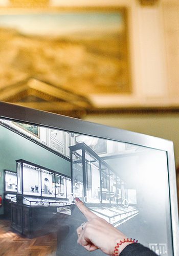 A woman in the museum uses the touchscreen monitor electronic guide, the concept of modern education